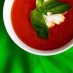 Bowl of tomato soup with ricotta cheese and basil leaves