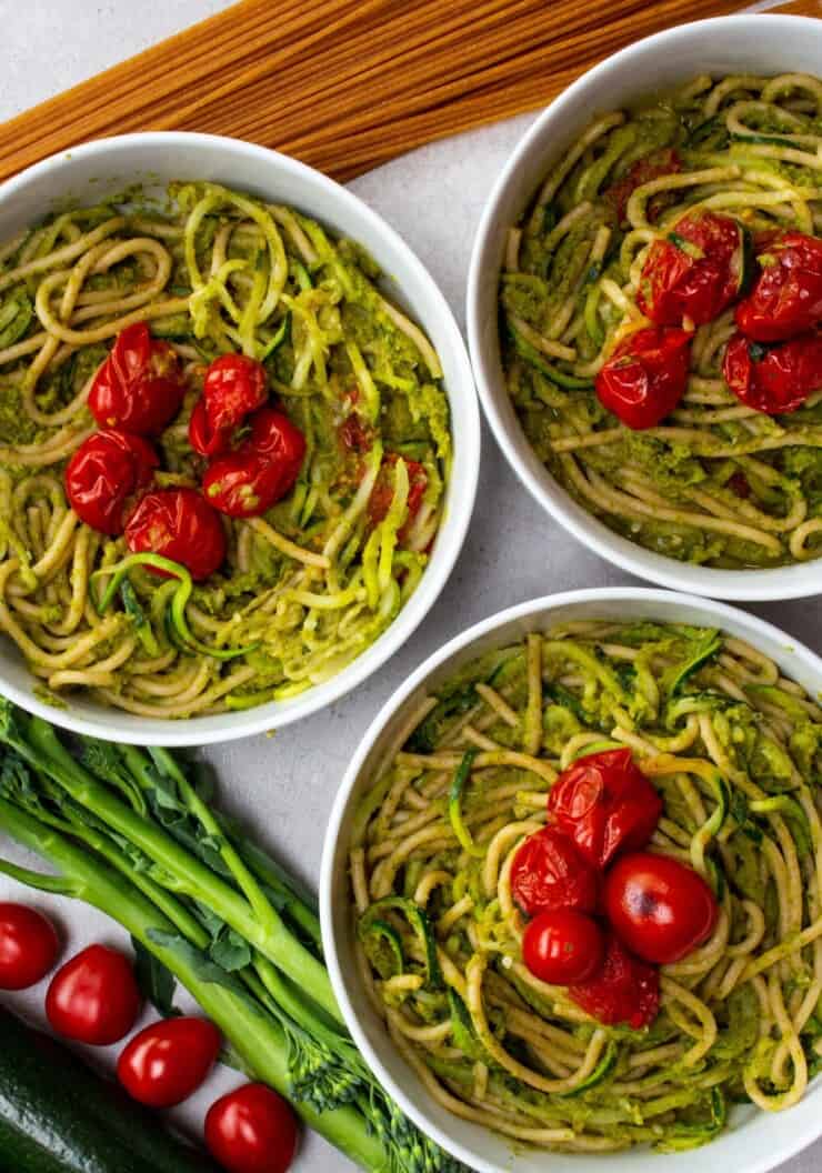 3 bowls of spaghetti mixed with pesto and topped with roasted tomatoes