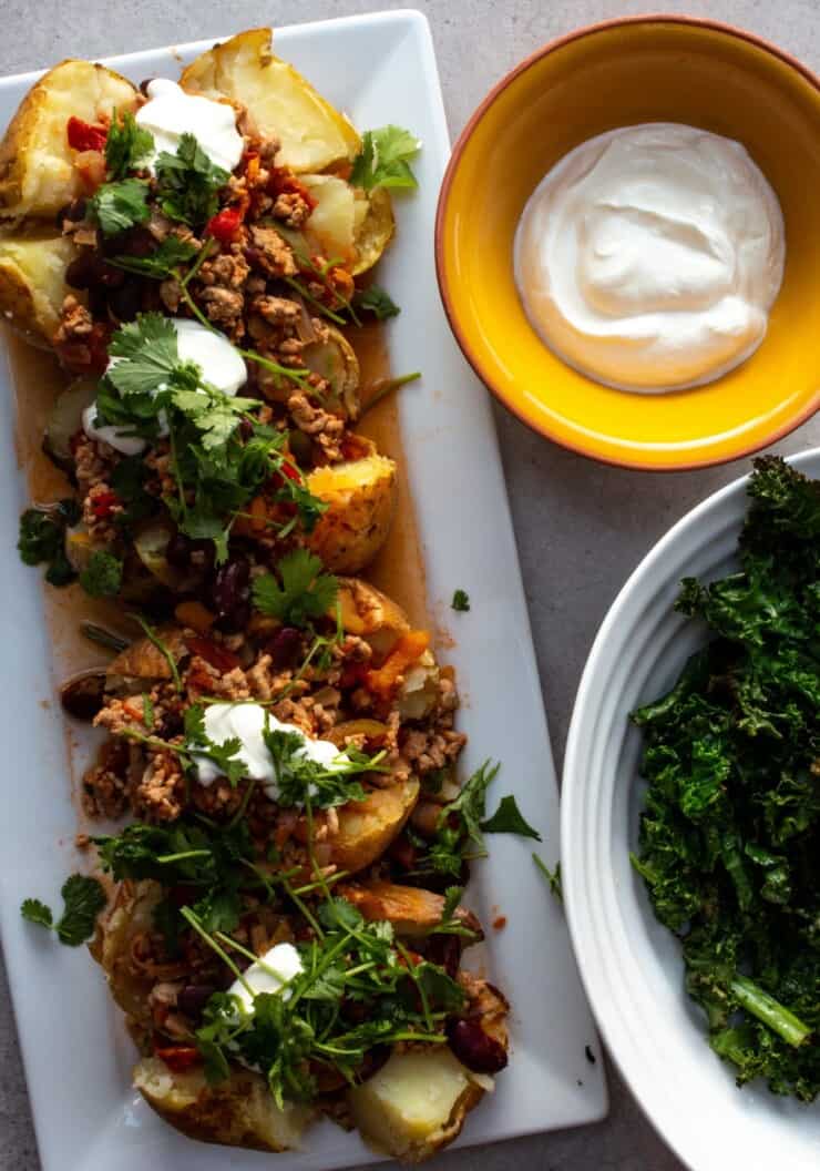Baked potatoes with chilli sauce and a bowl of sour cream