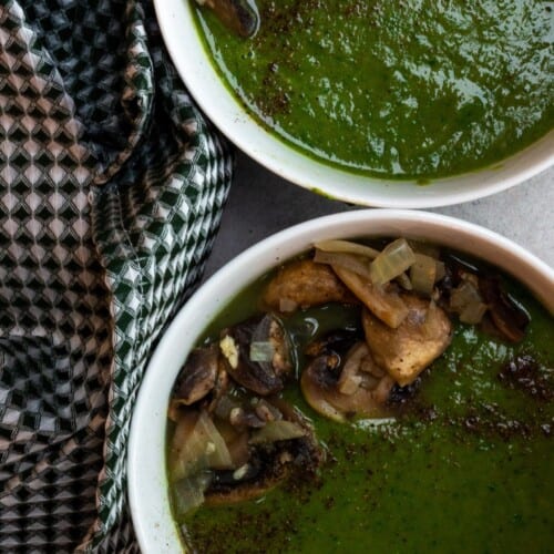 Spinach soup with mushroom topping in 2 white bowls