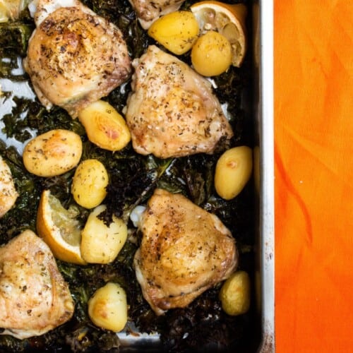 Golden brown chicken , new potatoes and kale on baking tray
