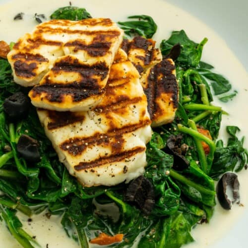 Slices of charred halloumi on a bed of spinach