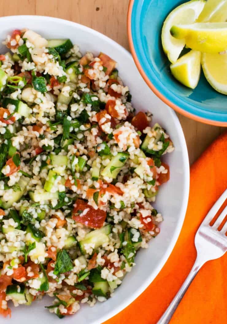 Tabbouleh salad in large bowl with lemons to garnish