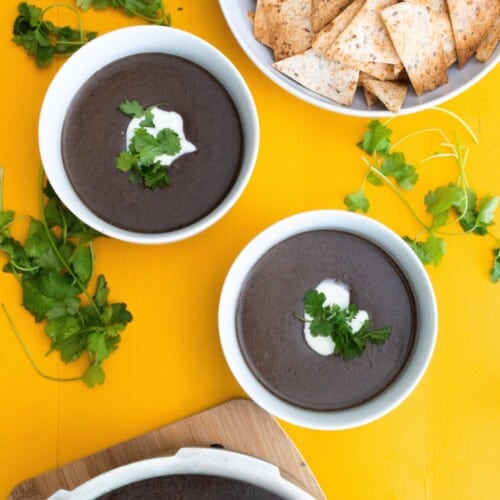 2 bowls of black bean soup with a bowl of tortilla chips