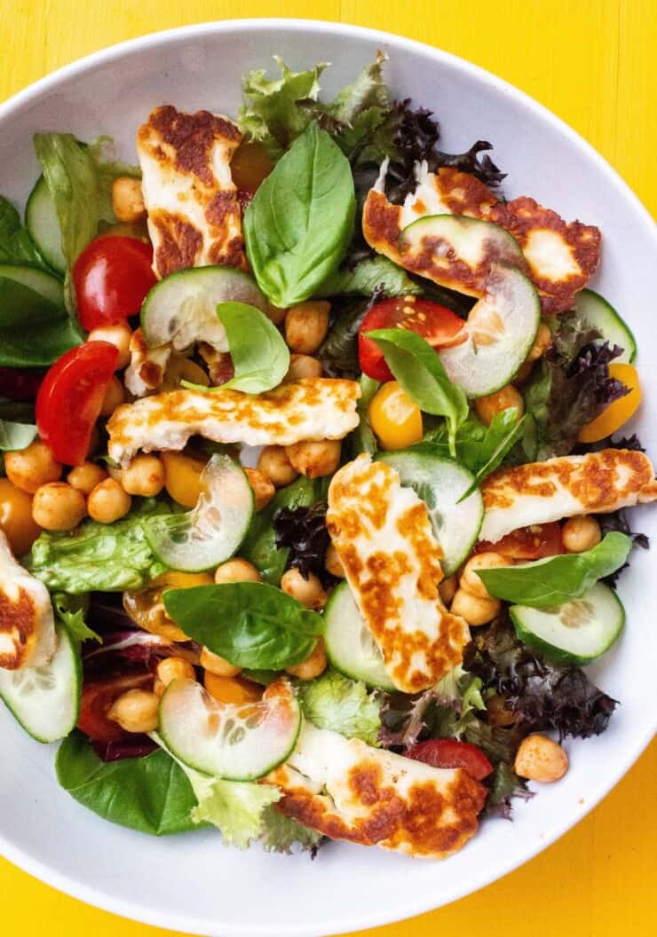 A bowl of golden brown fried halloumi on a bed of salad.