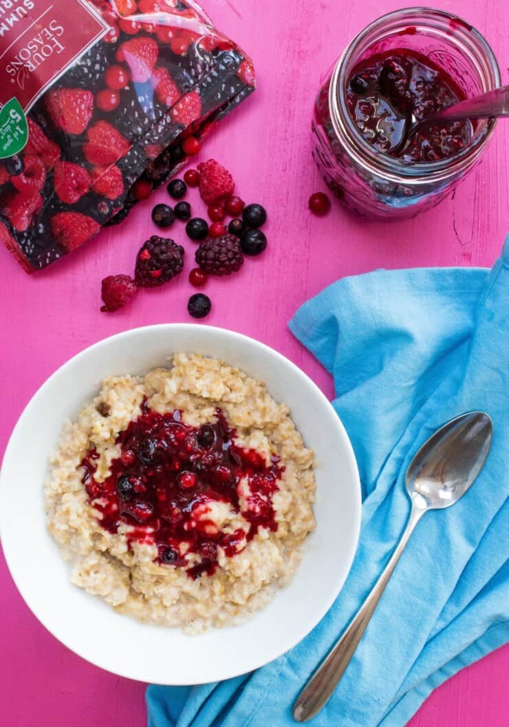 Overhead shot of bowl of porridge with berry topping and bag of berries