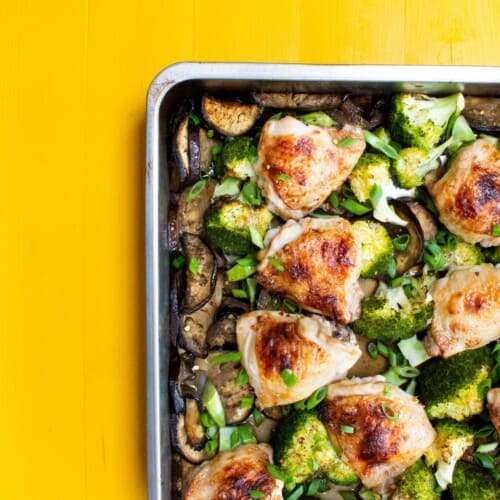 Overhead shot of golden browned chicken thighs and broccoli on a baking tray