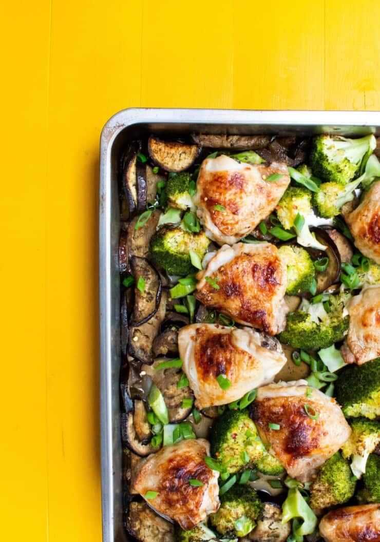 Overhead shot of golden browned chicken thighs and broccoli on a baking tray