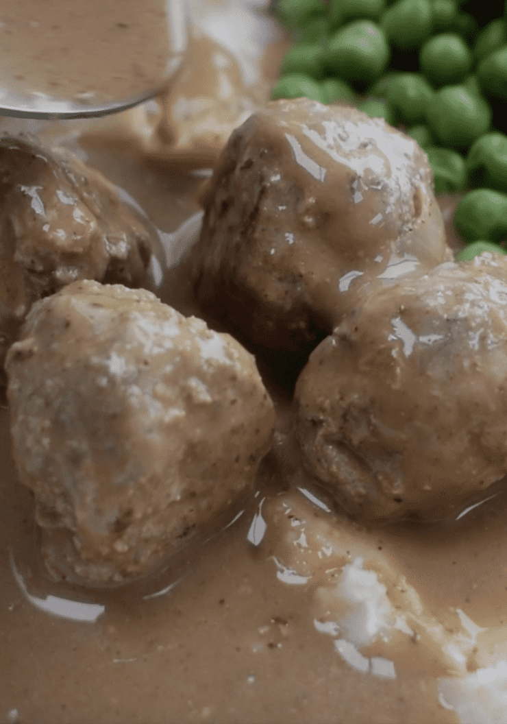 Close shot of meatballs in gravy with peas