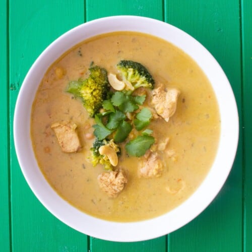 Overhead shot of bowl of chicken korma soup with broccoli and coriander topping