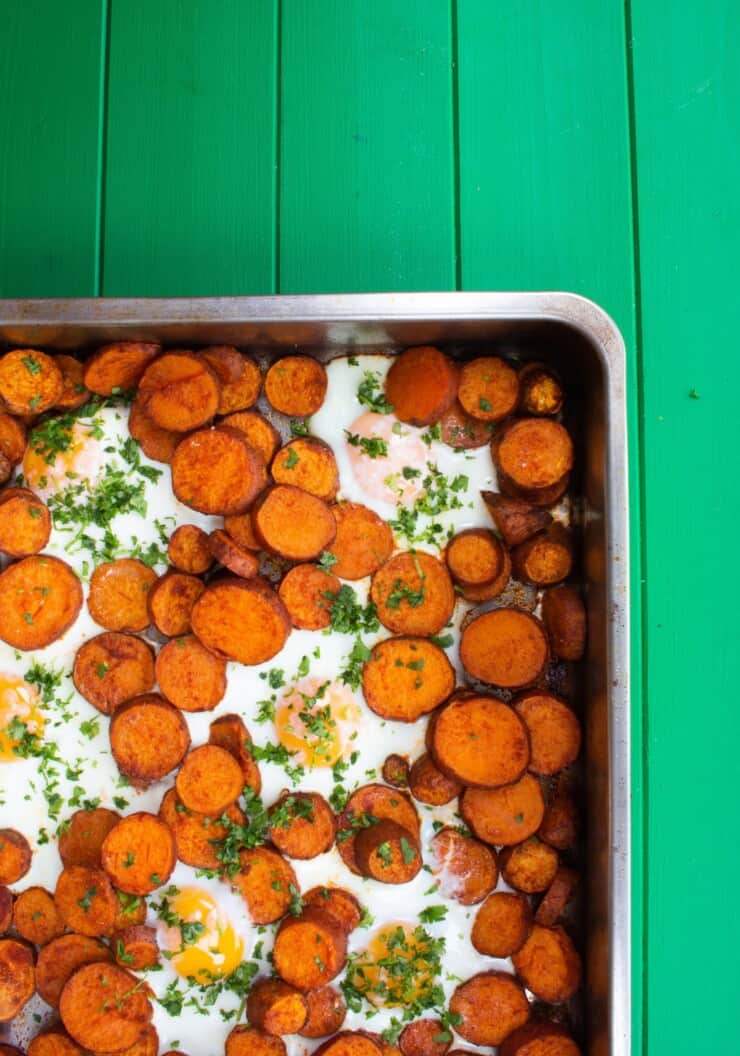 Overhead shot of sweet potato slices and cooked eggs in large baking tray