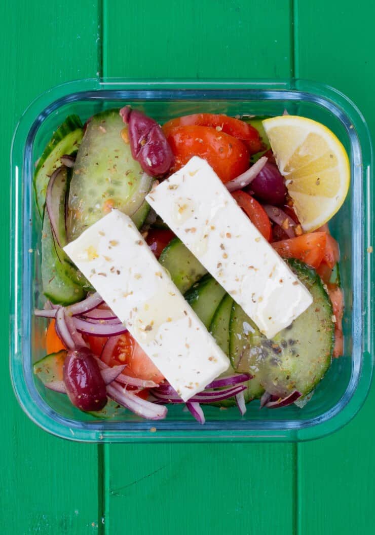Glass meal prep container with salad and 2 slices of feta cheese