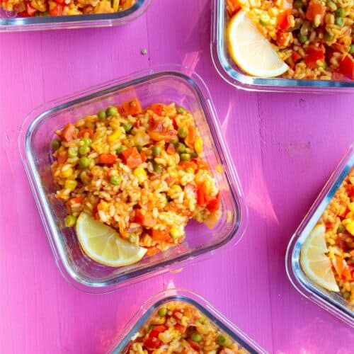 Loaded Vegetable Paella in 5 glass meal prep containers garnished with a wedge of lemon.
