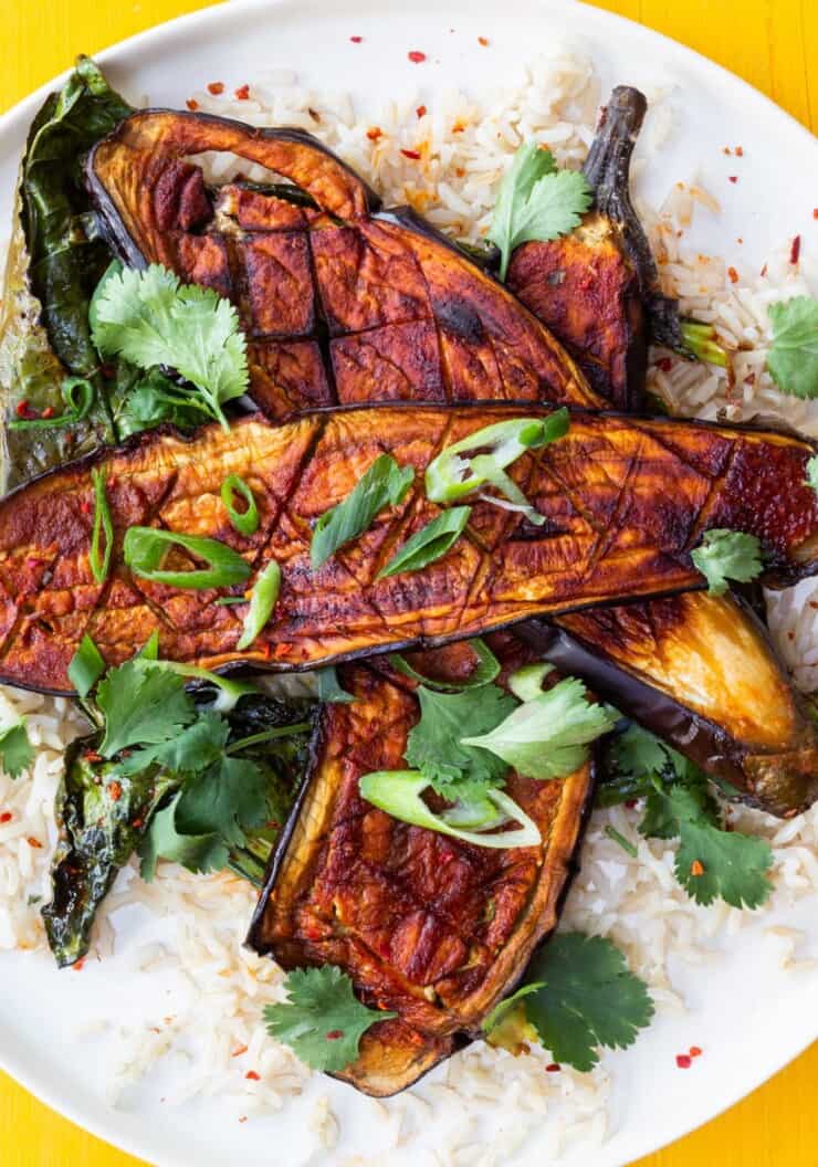 Overhead shot of roasted aubergine planks, over a bed of rice and topped with coriander