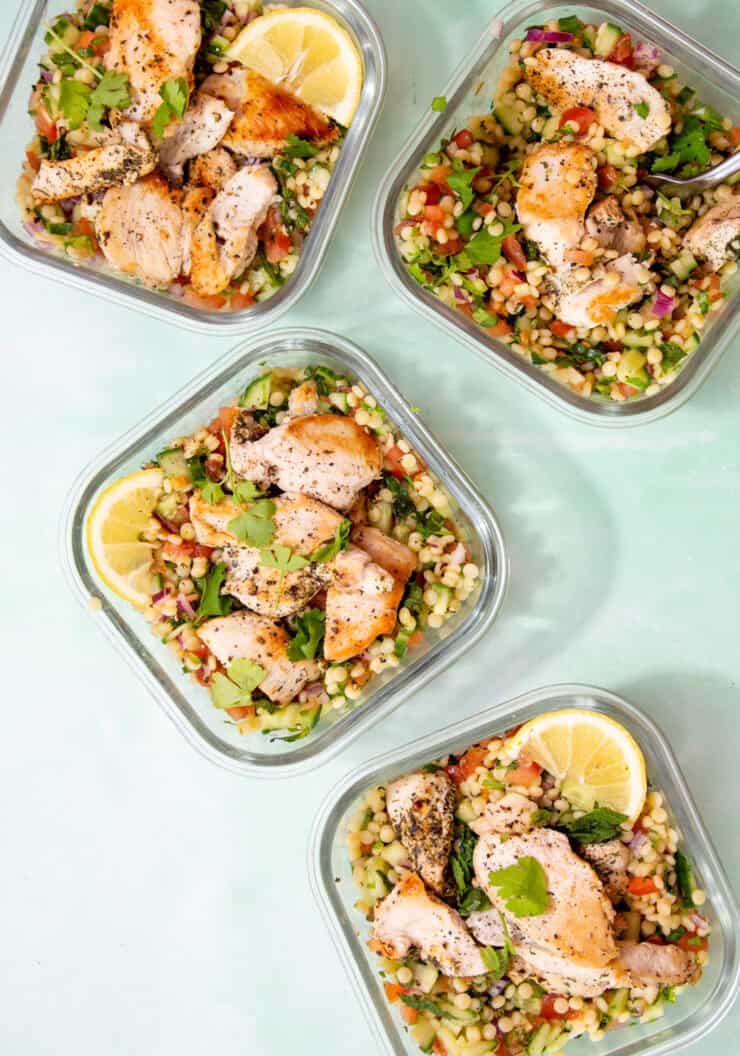 4 square glass meal prep containers with tabbouleh ginat cous cous salad with chicken.