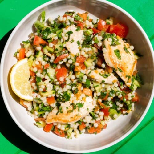 Overhead shot of bowl of salad with giant cous cous, chopped tomatoes. parsley and mint