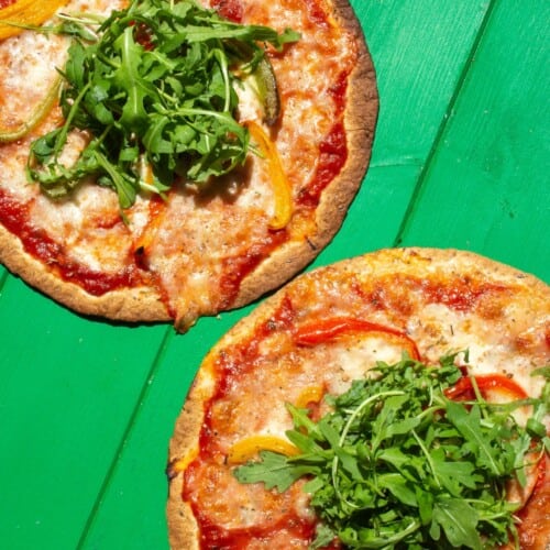 Overhead shot of 2 tortilla pizzas with cheese topping and rocket