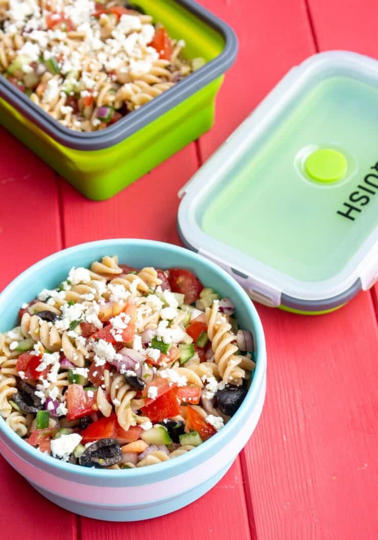 2 meal prep containers with Mediterranean Pasta Salad with Basil Oil topped with crumbled feta and the 2 container lids by side.