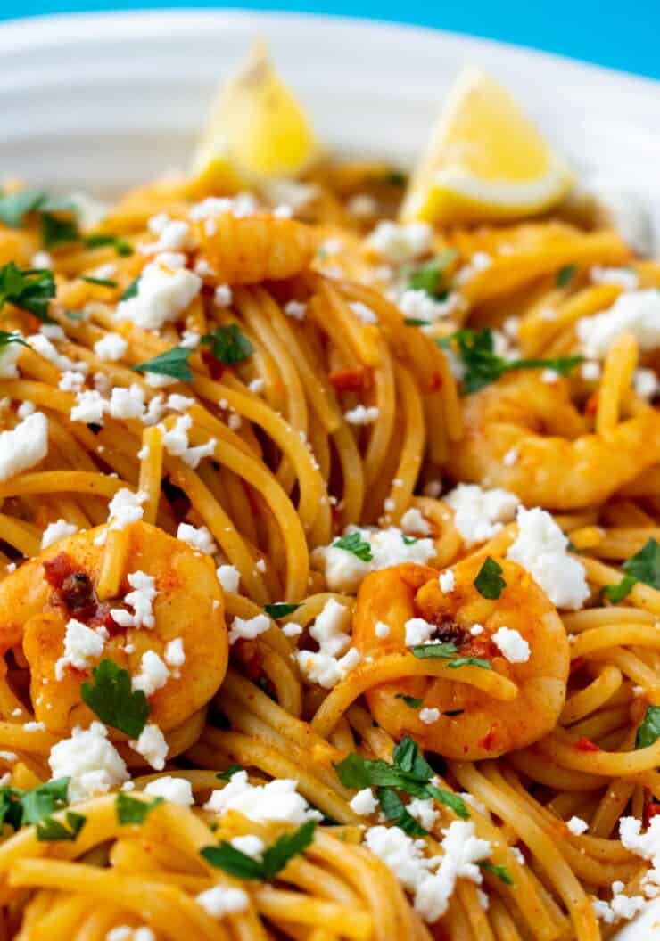 Overhead close up shot of spaghetti, with prawns and garnish with feta and parsley