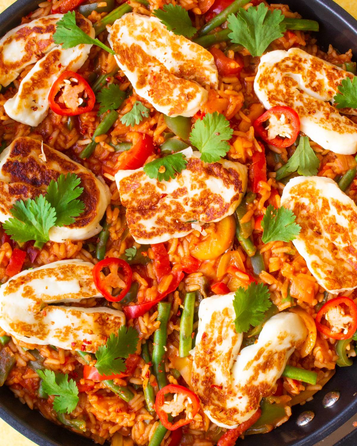 Close up of Spicy Tomato rice with golden browned halloumi and coriander topping.
