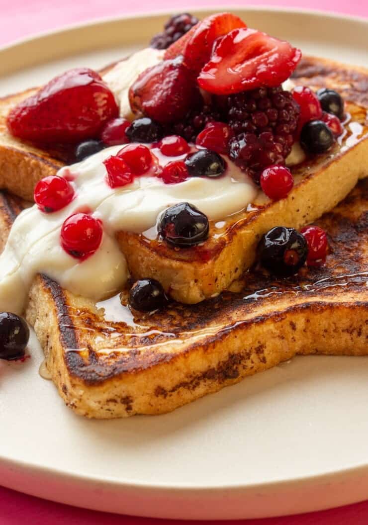 2 slices of Cinnamon French Toast with Mixed Berries and yogurt on a plate.