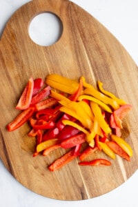Sliced peppers on a wooden chopping board.