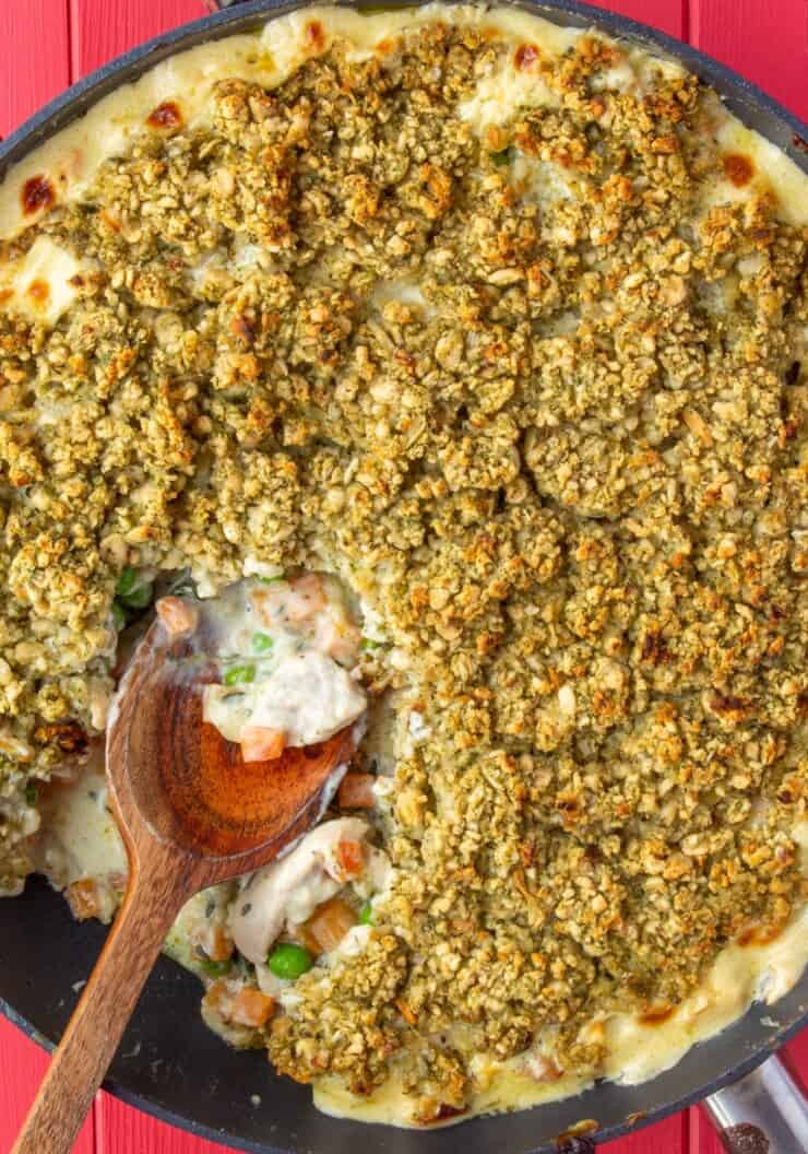 Overhead shot of chicken pot pie with a stuffing crust in large pan with a wooden spoon