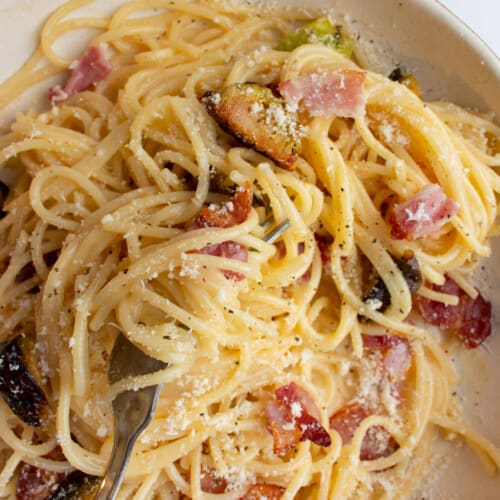 Close up of Brussel sprout carbonara with bacon and grated parmesan.