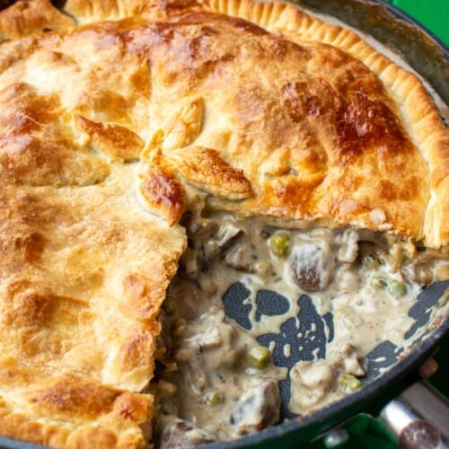 Overhead shot of Creamy Mushroom, Leek and Aubergine Pot Pie tin large pan with 1 large piece taken out