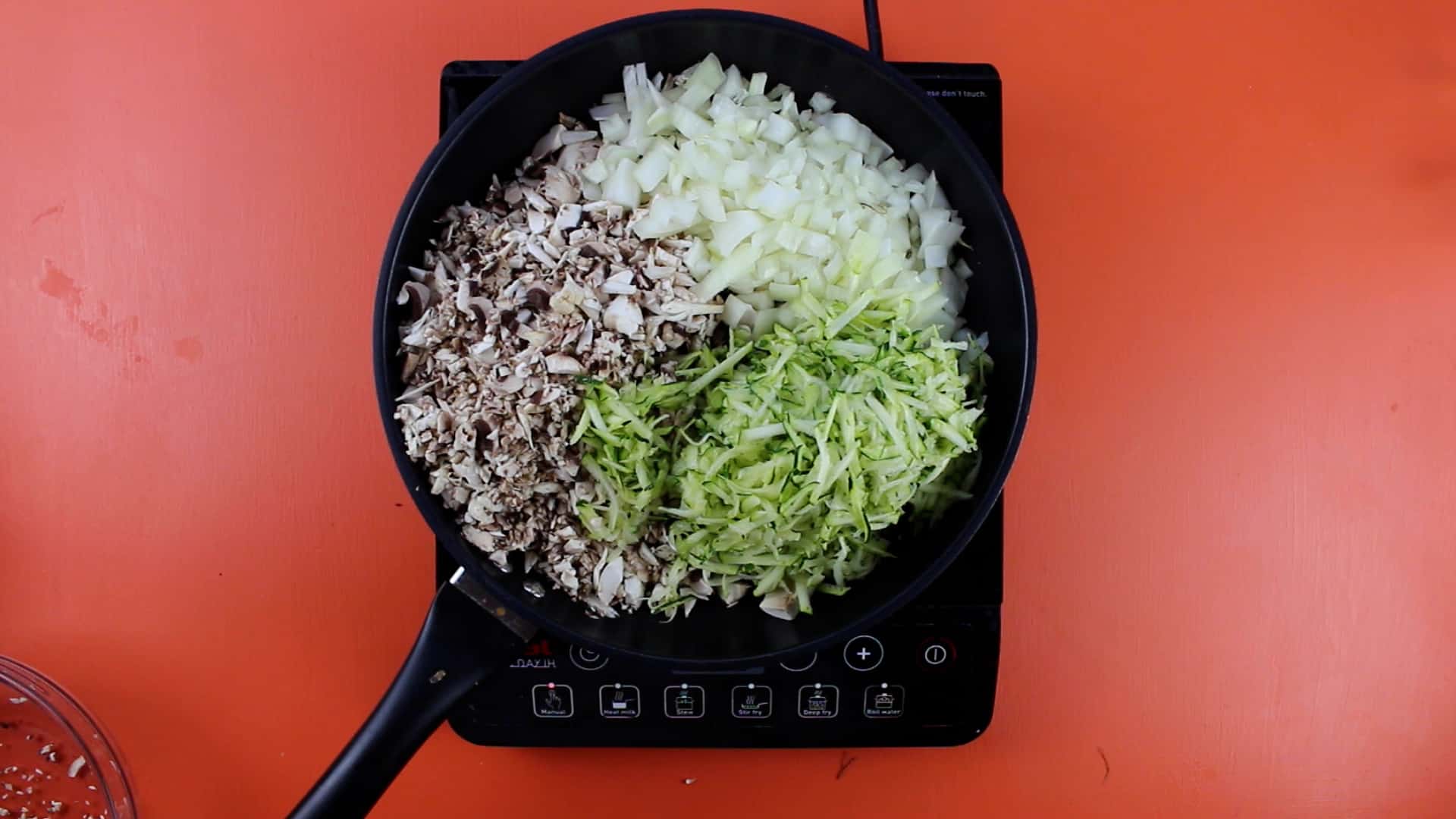 Chopped onions, courgette and mushrooms in frying pan