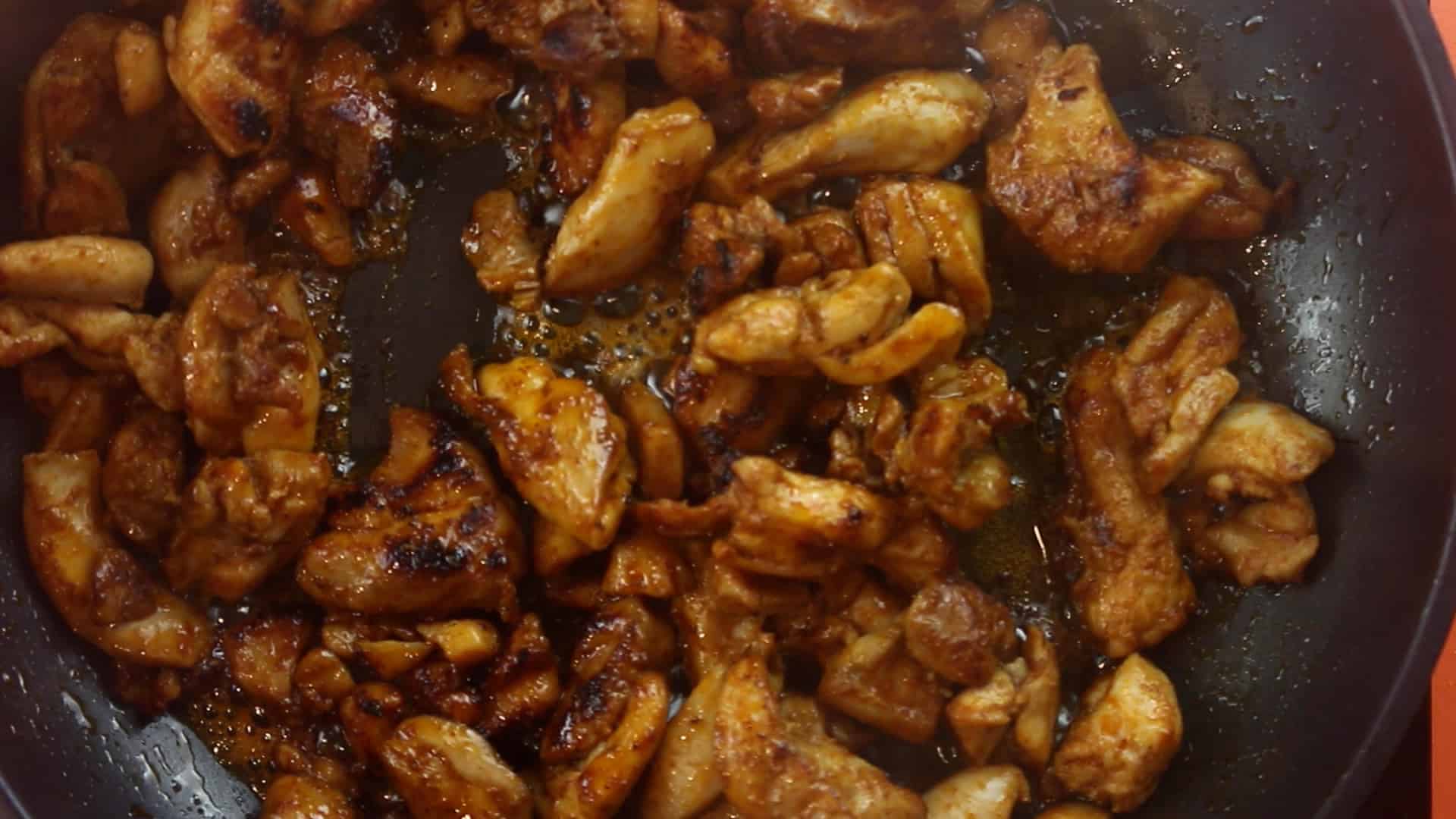 Browned and cooked chicken pieces in a pan on stove.