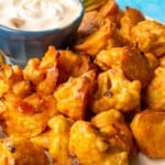 Close up of Crispy Baked Cauliflower Bites with Chilli Mayo in a small bowl on the plate with a blue background.