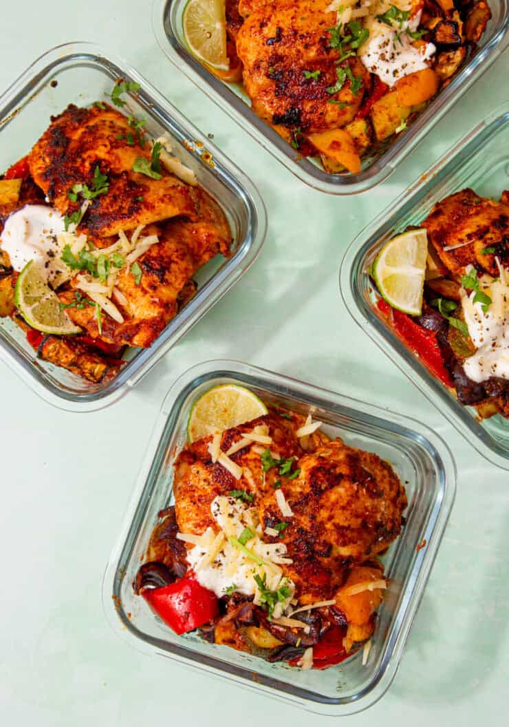 4 square glass meal containers with Low Carb Mexican Inspired Chicken with broccoli, peppers, red onion with sour cream, cheese and limes.