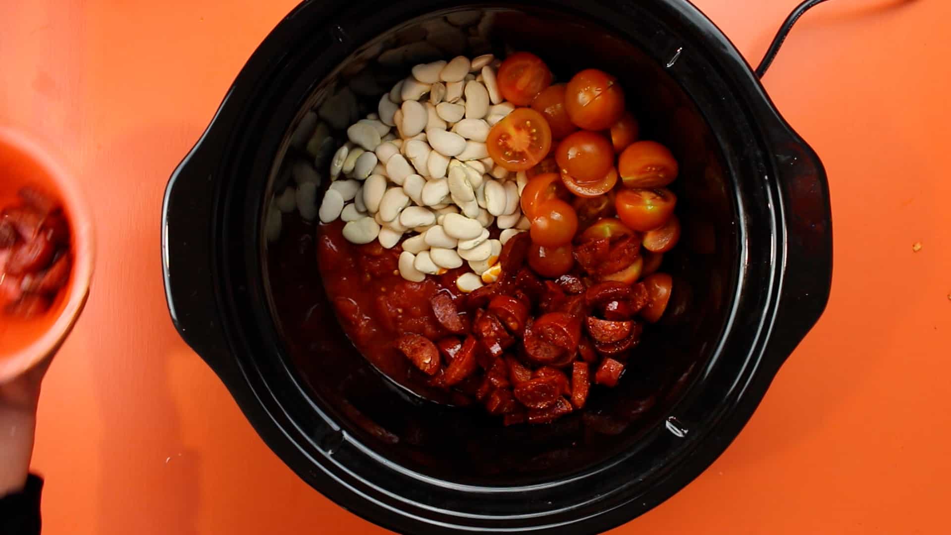 Chorizo, cherry tomatoes and butter beans in slow cooker.