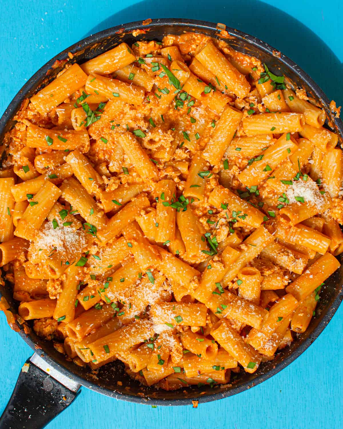Overhead shot of Spicy Vodka Rigatoni in large pan with blue background