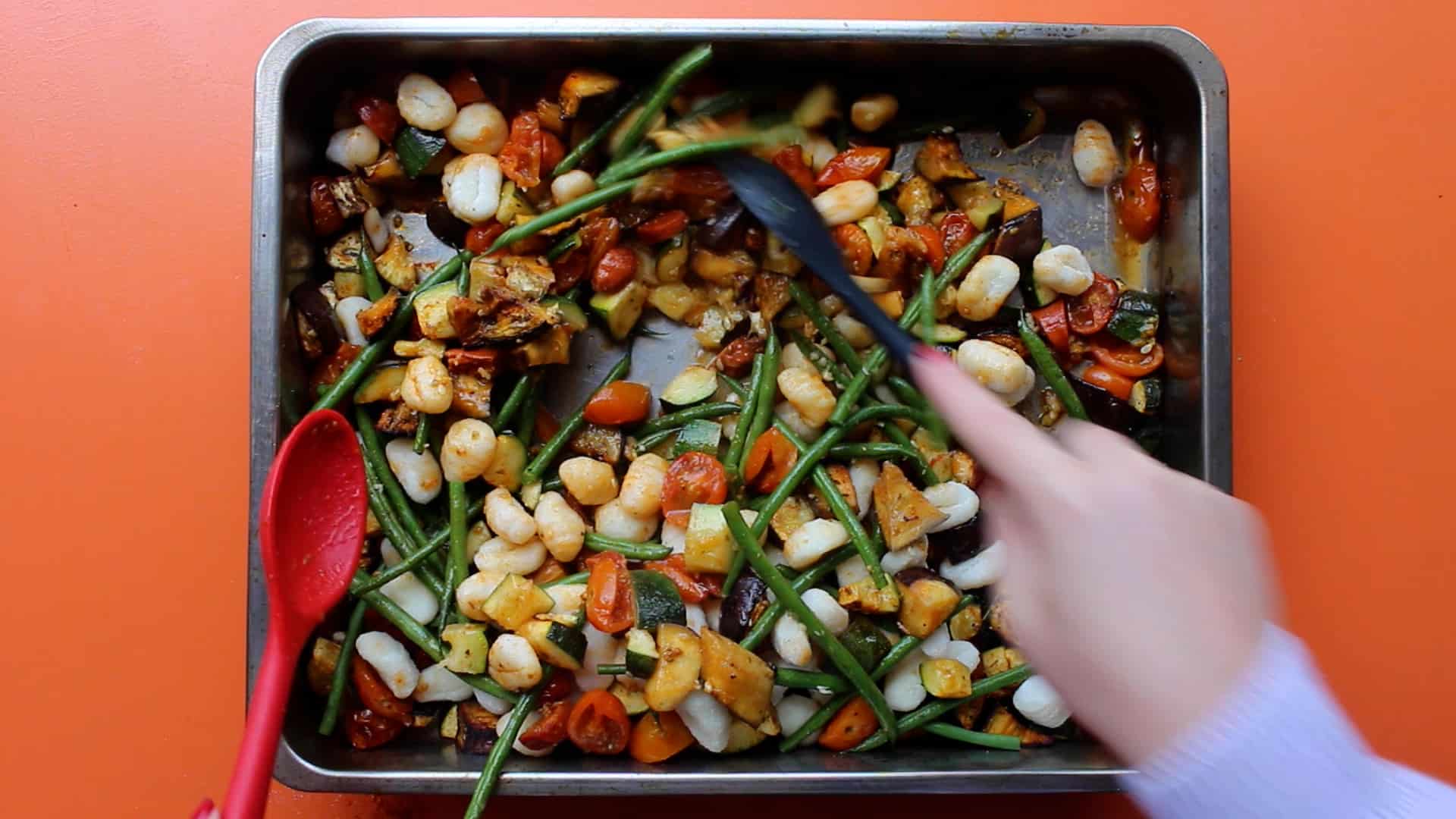 Gnocchi, green beans, chorizo and roasted vegetables mixed together in the baking tray.