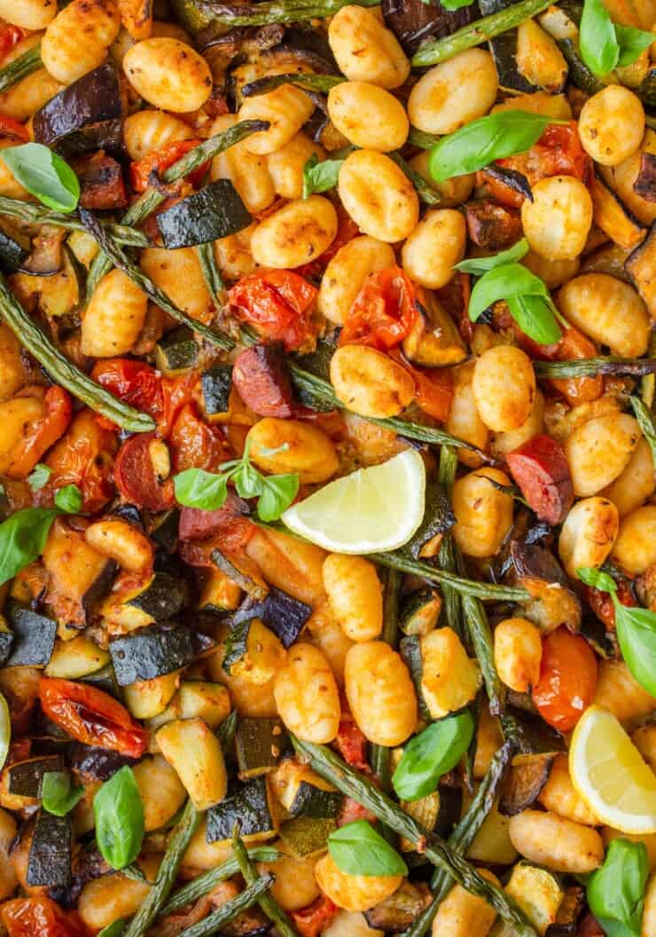 Close up of Crispy Roasted Gnocchi with Chorizo and Vegetables with green beans and a wedge of lemon.