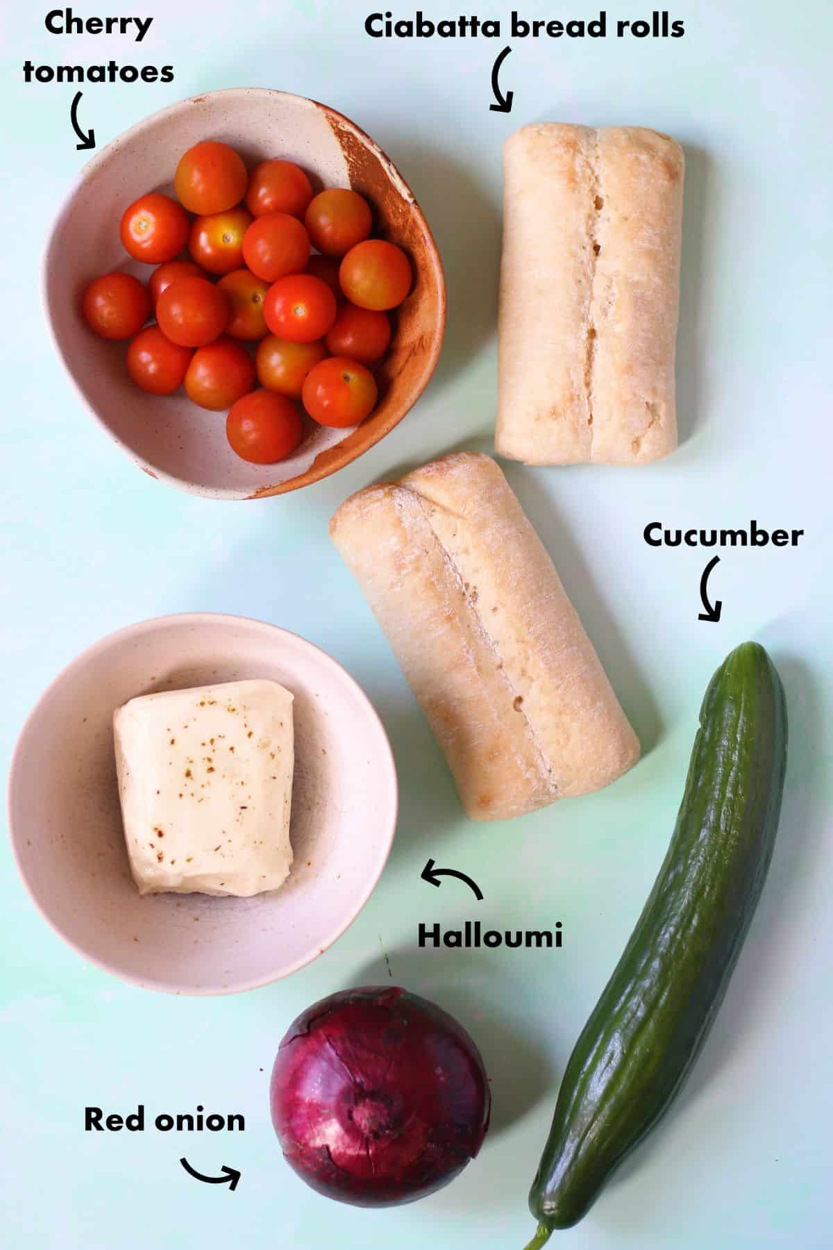 Ingredients to make Halloumi bread salad laid out on a pale blue background and labelled.