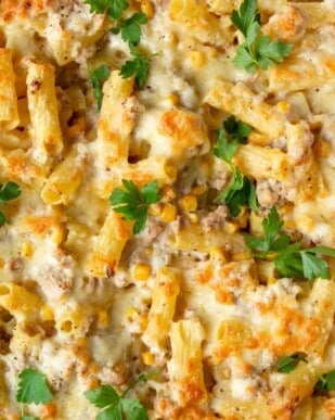 Close up of Creamy tuna pasta bake with sweetcorn and topped with fresh parsley.