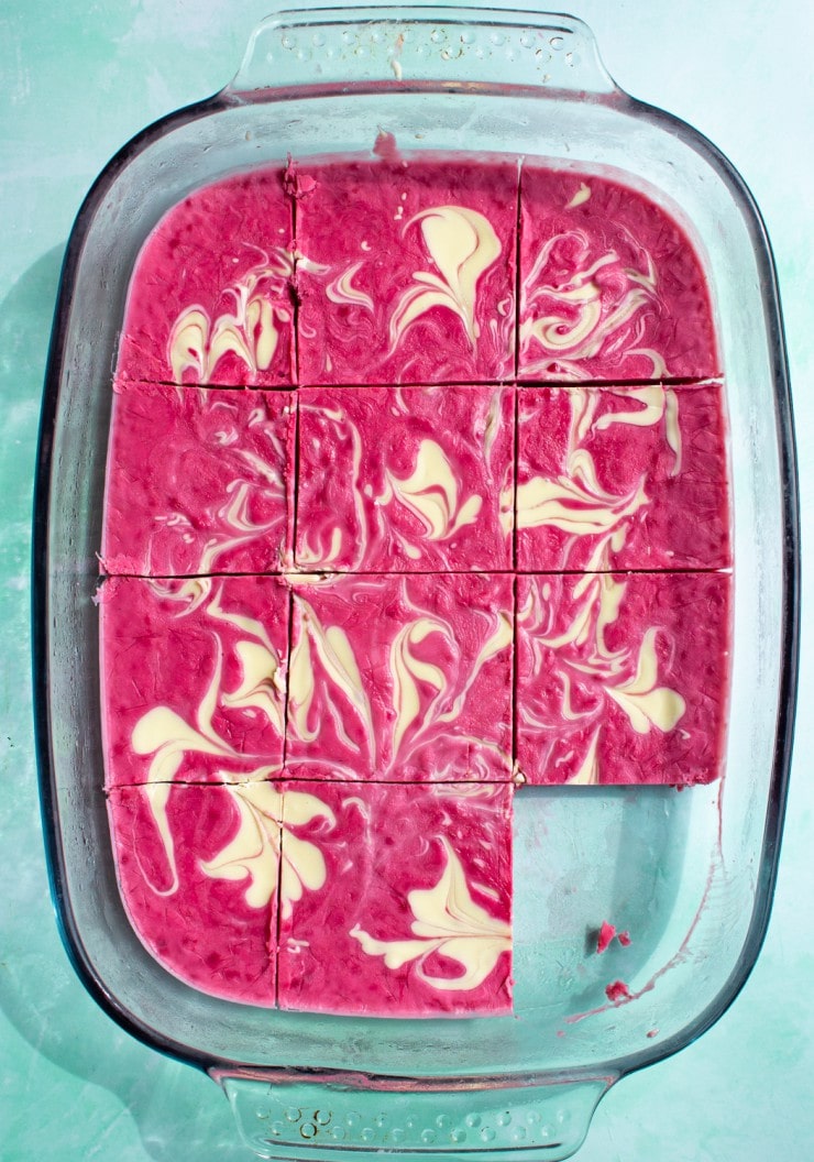 Raspberry and White Chocolate Yogurt Bark in a glass tray with a piece taken out of it