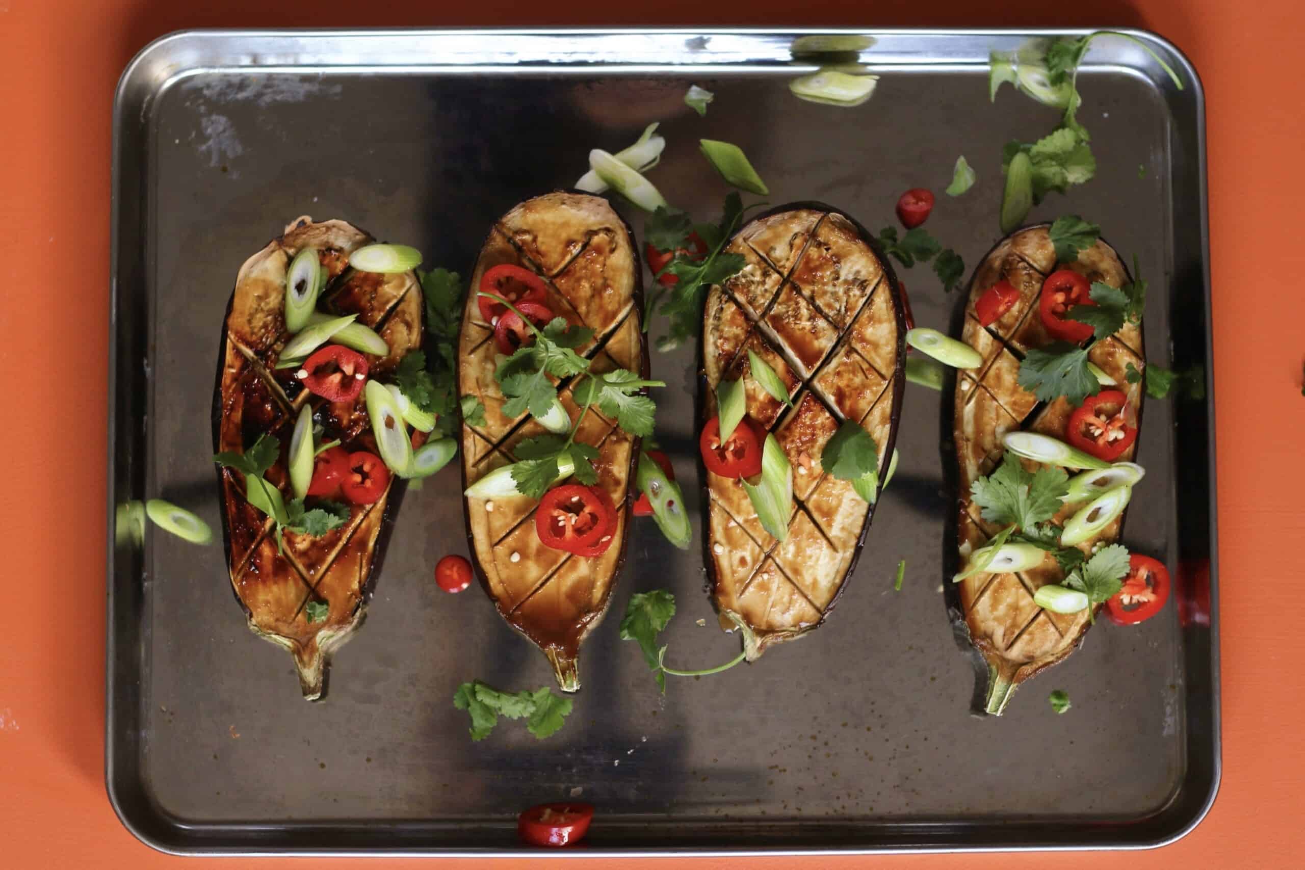 Baked aubergines with sliced chilli and coriander on baking tray