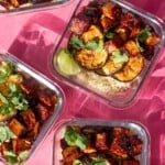 Crispy soy tofu, aubergine & rice in 4 meal prep containers topped with coriander and a wedge of lime on a pink background.