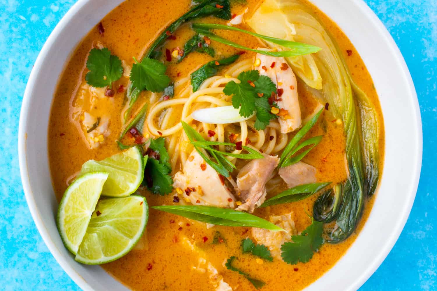 ramen with thick noodles, topped with lime, coriander, spring onion and chilli flakes