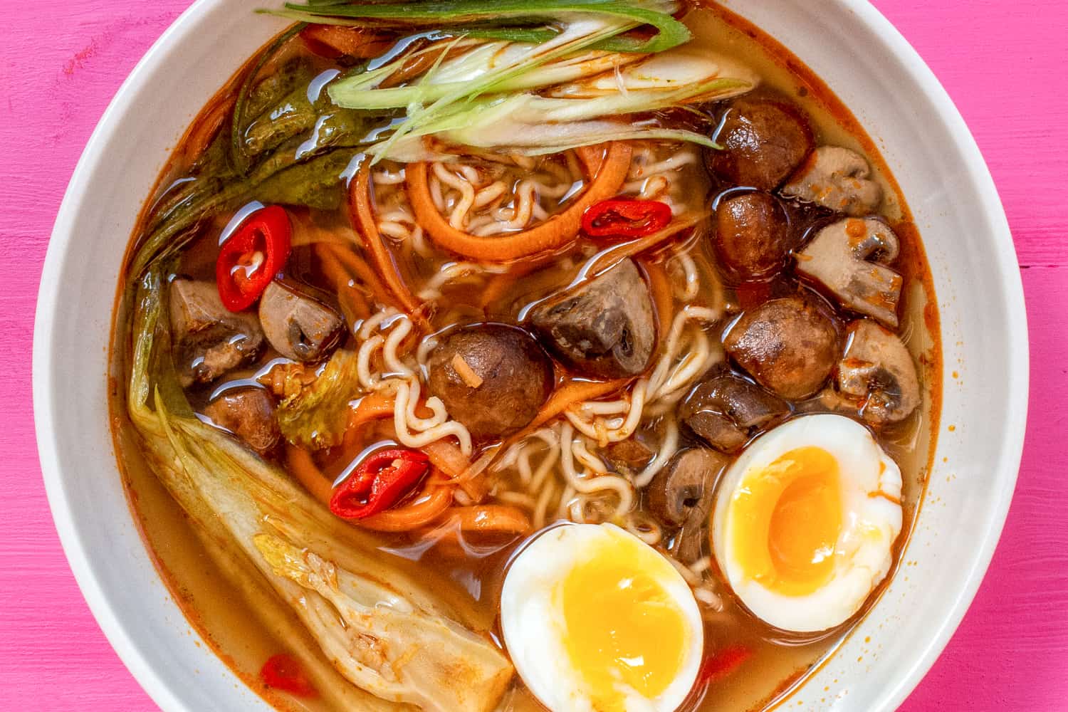 ramen bowl filled with pak choi, spiralized carrot, boiled egg and chillies