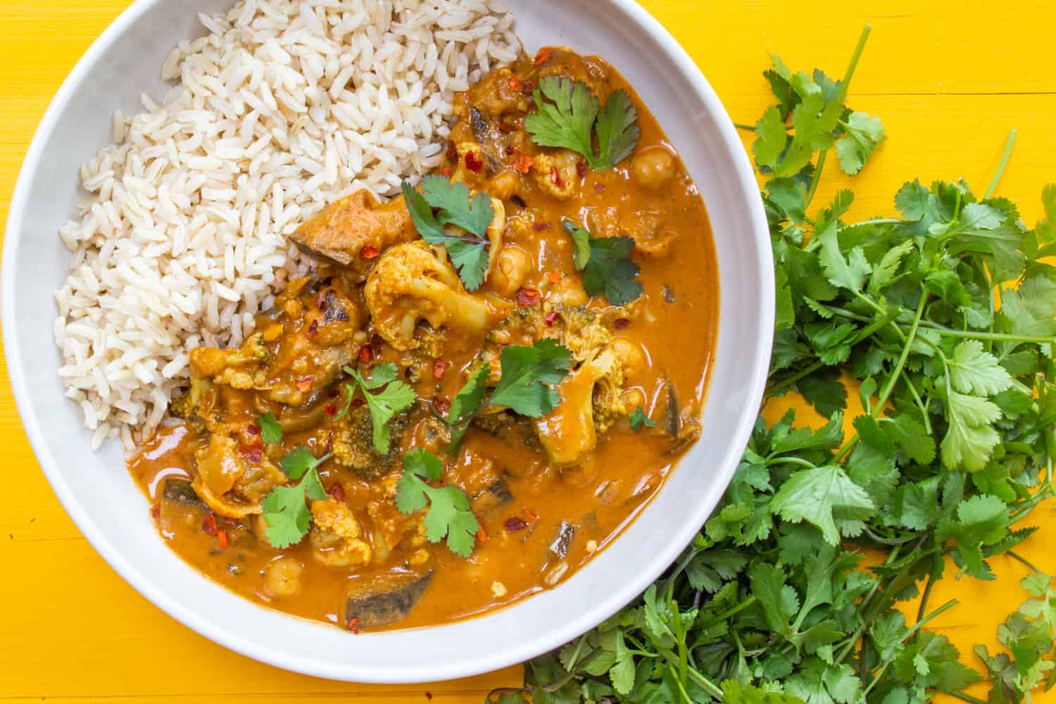 orange curry served with brown rice and topped with coriander 