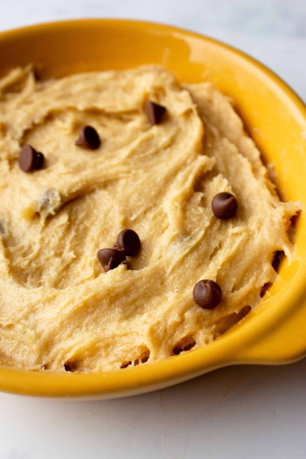 Close up of cookie dough with chocolate chips in a bowl.