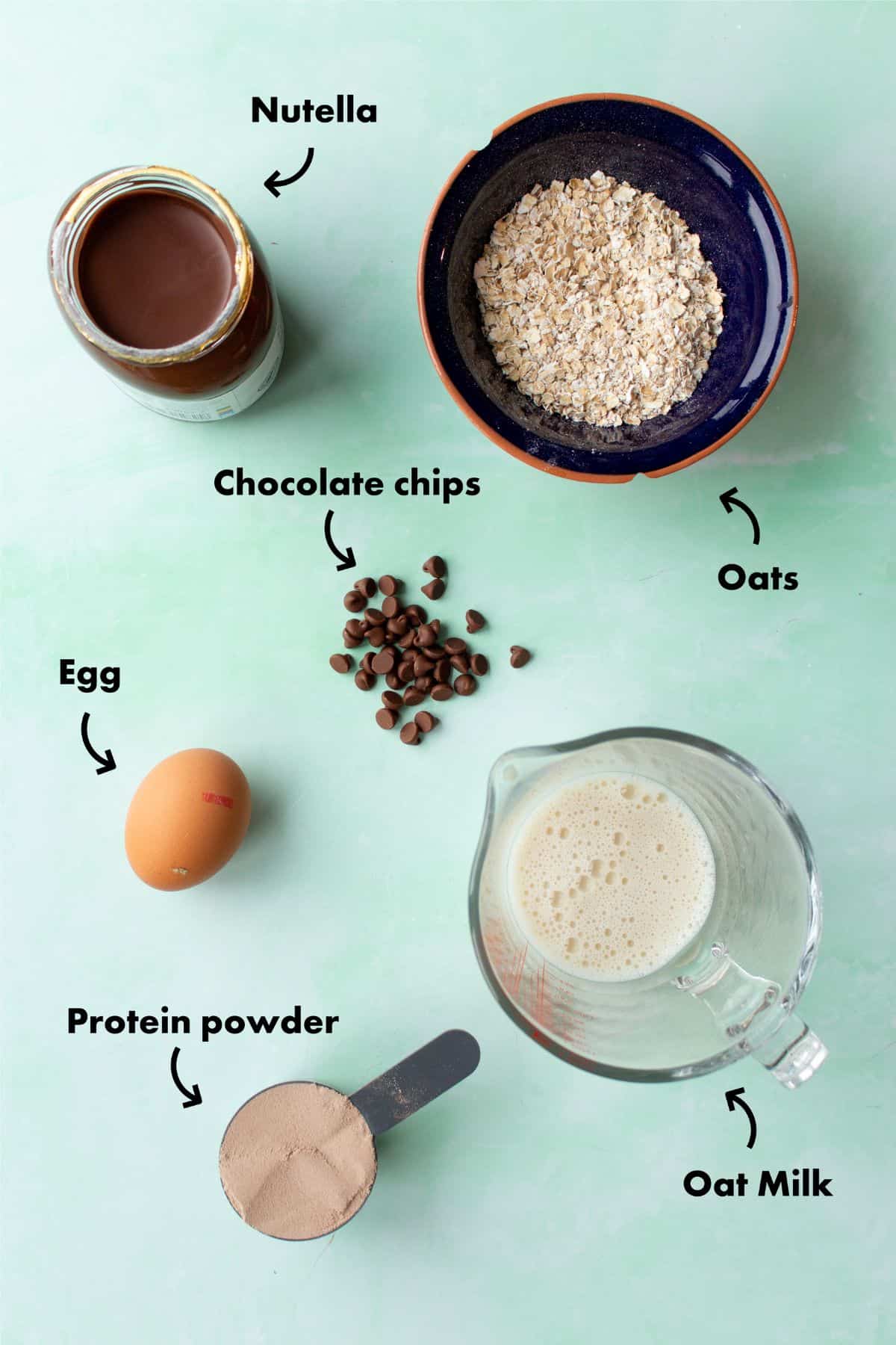Ingredients to make the choclate baked oats laid out on a pale blue background and labelled.