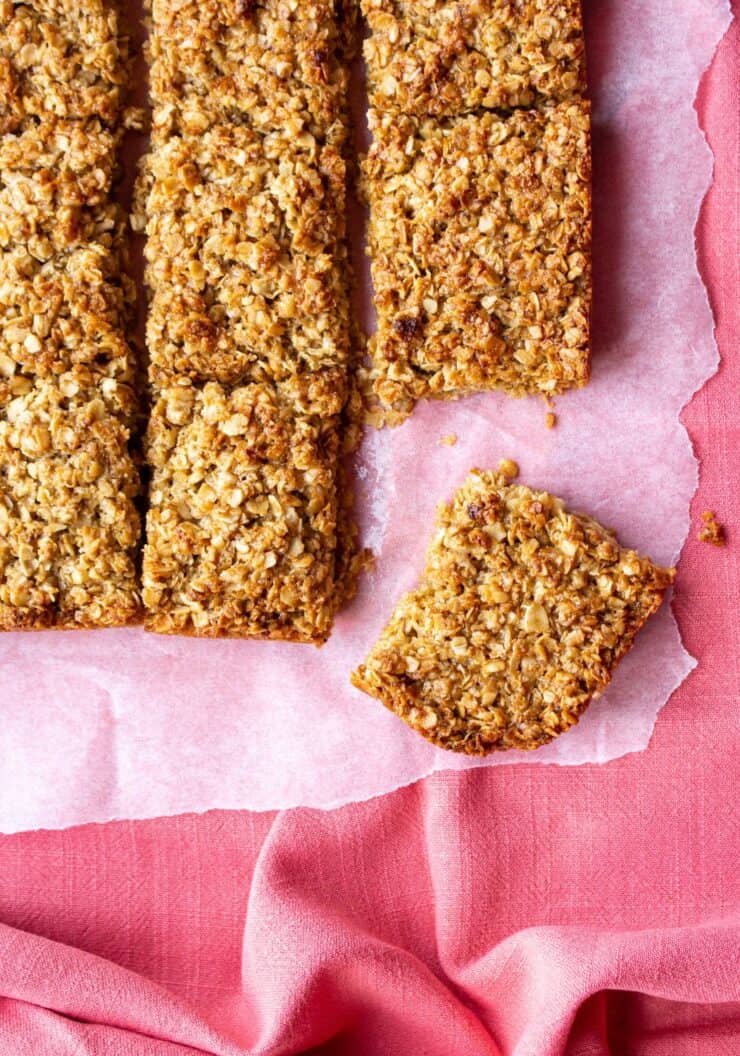 Pieces of Flapjacks on parchment paper on a pink cloth.
