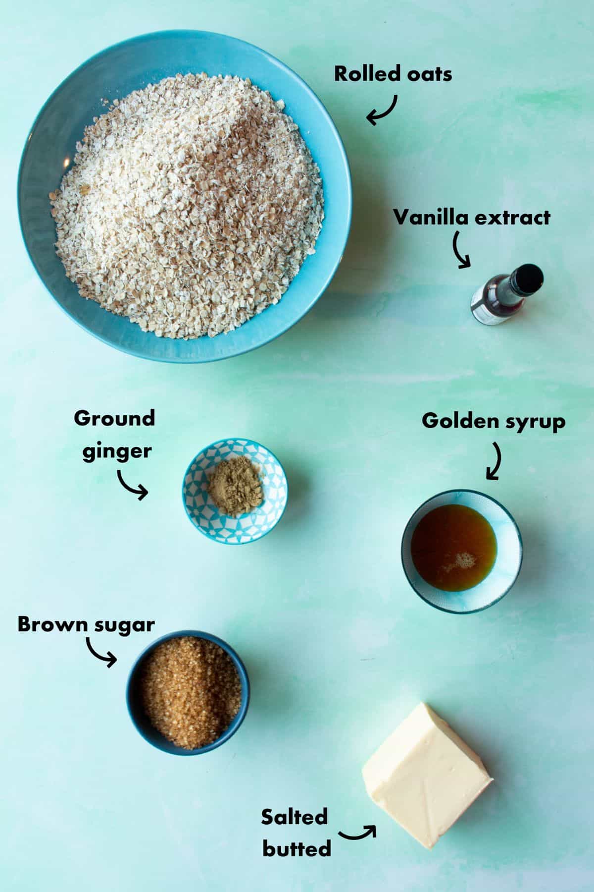 Ingredients to make the flapjacks load out on a pale blue background and labelled.