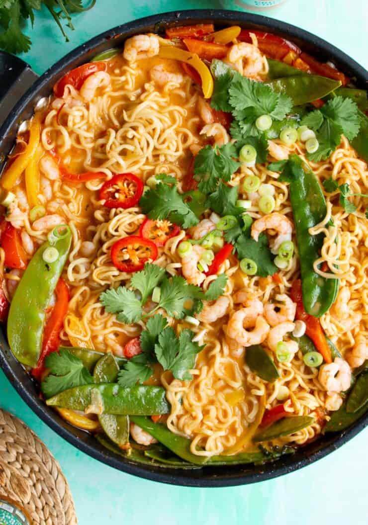Prawn curry with noodles, mange tout, peppers and fresh corainder in a large pan.